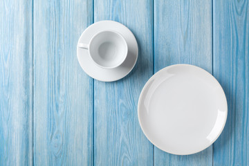 Empty plate and coffee cup on blue wooden background
