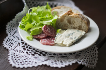 Gorgonzola cheese, sausage and ciabatta on a white plate 
