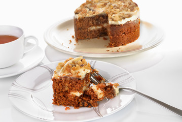 Carrot cake slice served on a plate with fork on a white surface