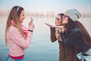 Girlfriends taking a photo of them sending kiss