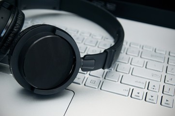 Wireless headphones on laptop keyboard. Music and gaming concept