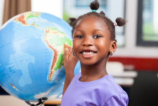African girl touching world globe at school