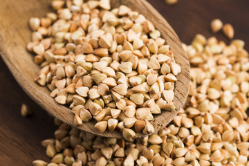 Buckwheat with a spoon on a wooden boards background
