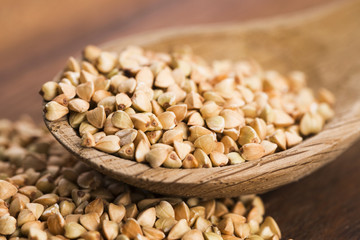 Buckwheat with a spoon on a wooden boards background