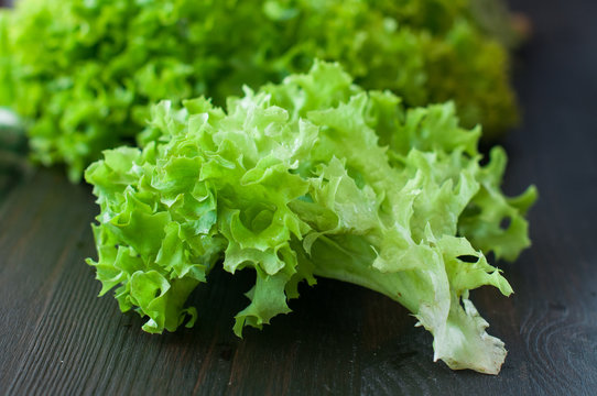 fresh green salad leaves (lettuce) on black wooden table