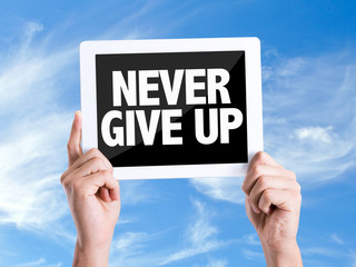 Tablet pc with text Never Give Up with sky background