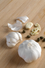 Garlic Cloves with Capers on Wood Cutting Board
