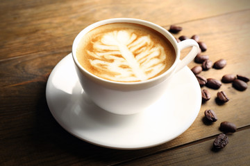 Cup of coffee latte art with grains on wooden background