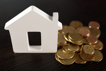 Obraz na płótnie Canvas Model of house with coins on wooden table, closeup