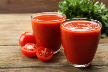 Glasses of fresh tomato juice on wooden background