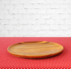 Empty round wooden tray on red polka dot tablecloth.
