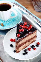 Delicious chocolate cake with berries and cup of coffee on table close up