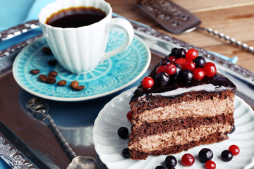 Delicious chocolate cake with berries and cup of coffee on table close up