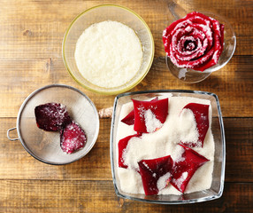 Making candied rose flower petals with egg whites and sugar, on wooden background