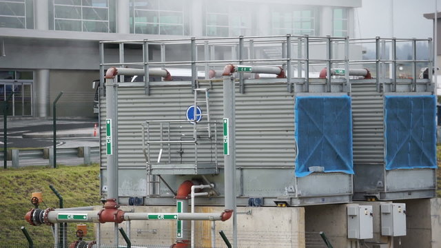 Static shot of a large industrial type HVAC or heating ventilation air conditioning unit making steam because of the difference in temperature and the humidity in the air.