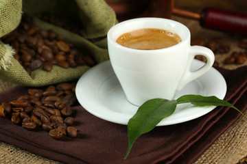Cup of coffee with beans on table close up