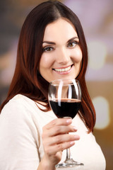 Young woman tasting wine on bright background