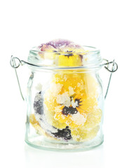 Candied sugared violet flowers in glass jar, isolated on white