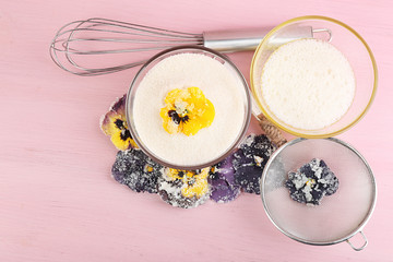 Making candied violet flowers with egg whites and sugar, on color wooden background