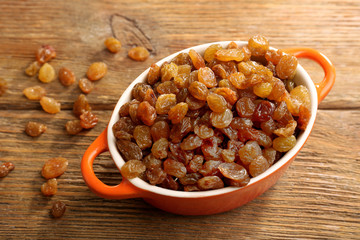 Raisins in pan on wooden table, closeup