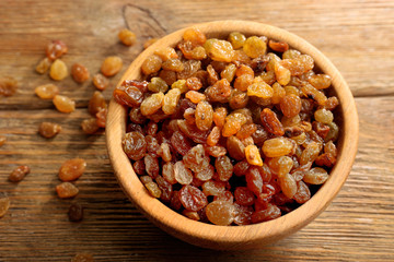Raisins in bowl on wooden table, closeup