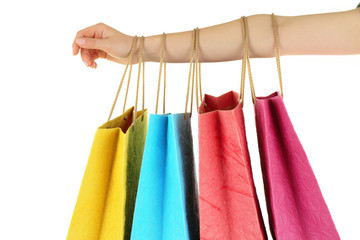 Female hand with colorful shopping paper bags isolated on white