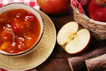 Apple jam and fresh red apples on wooden table close-up