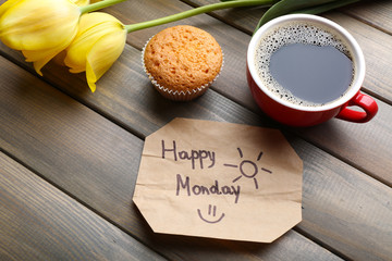 Cup of coffee with fresh cupcake, tulips and Happy Monday massage on wooden background