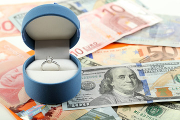 Wedding ring in box  on banknotes background. Marriage of convenience