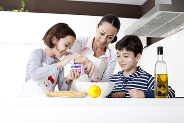 Familia sonriente preparando una torta en la cocina