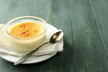 Creme brulee dessert  on napkin, on color wooden background