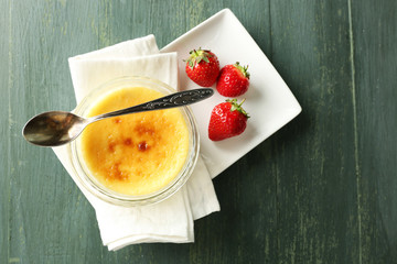 Creme brulee dessert on napkin, on color wooden background