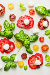 various of sliced tomatoes with mozzarella cheese and fresh basil, top view