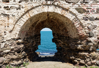 View of blue sea and sky from hole in old stonewall wall - 84291467