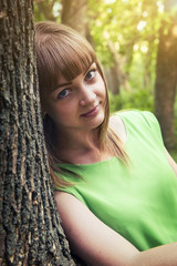Naklejka premium Young sensual girl leaning against a tree