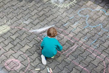 Obraz na płótnie Canvas Little blond boy painting with colorful chalks outdoors