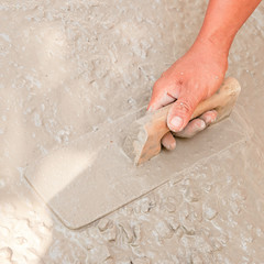 Asian plasterer hand plastering a floor