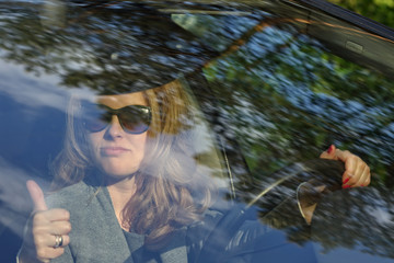 Young woman driver with thumb up - obrazy, fototapety, plakaty