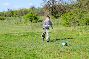 Fototapeta premium Boy Kicking Colorful Soccer Ball in Field