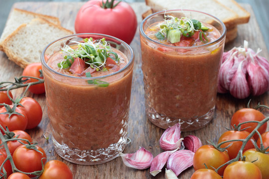 Two glasses of freshly prepared gazpacho with vegetable topping.