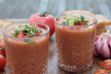 Two glasses of freshly prepared gazpacho with vegetable topping.
