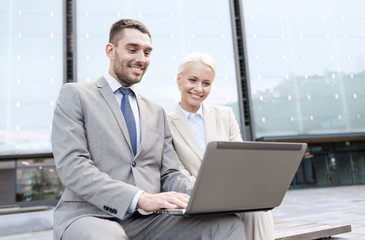 Fototapeta na wymiar smiling businesspeople with laptop outdoors