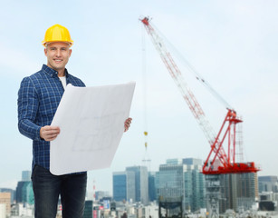 smiling male builder in helmet with blueprint