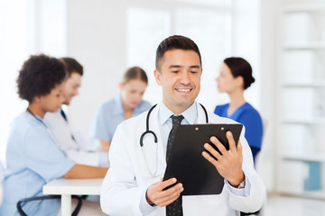 Fototapeta premium happy doctor with clipboard over medical team