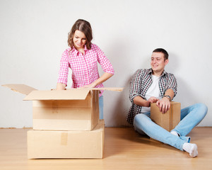 Happy young couple unpacking or packing boxes