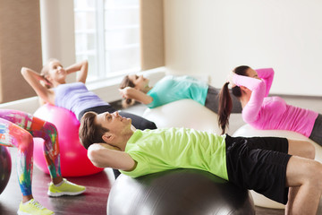 happy people flexing abdominal muscles on fitball