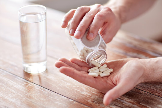 close up of man pouring pills from jar to hand