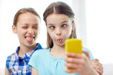 happy girls with smartphone taking selfie at home