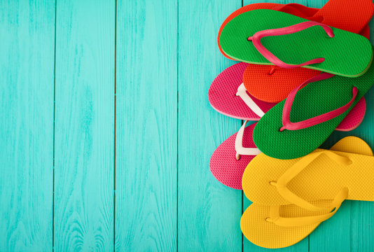 Colorful flip flops on blue wooden background