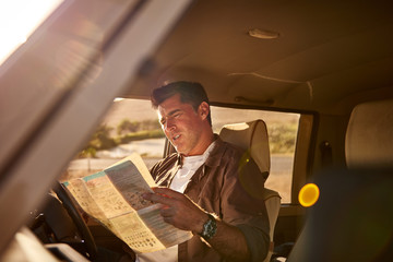 Man checking directions on a map in a car